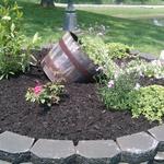Raised circular paver bed utilizes wine barrel and a variety of perennials and annuals creating instant color and dimension.